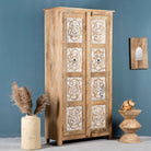 Side angle image of a hand carved wooden wardrobe made of solid mango wood with whitewashed floral details; Ibiza-style mango wood wardrobe, 190 × 100 × 40 cm.