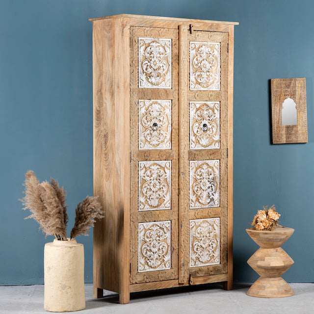 Side angle image of a hand carved wooden wardrobe made of solid mango wood with whitewashed floral details; Ibiza-style mango wood wardrobe, 190 × 100 × 40 cm.