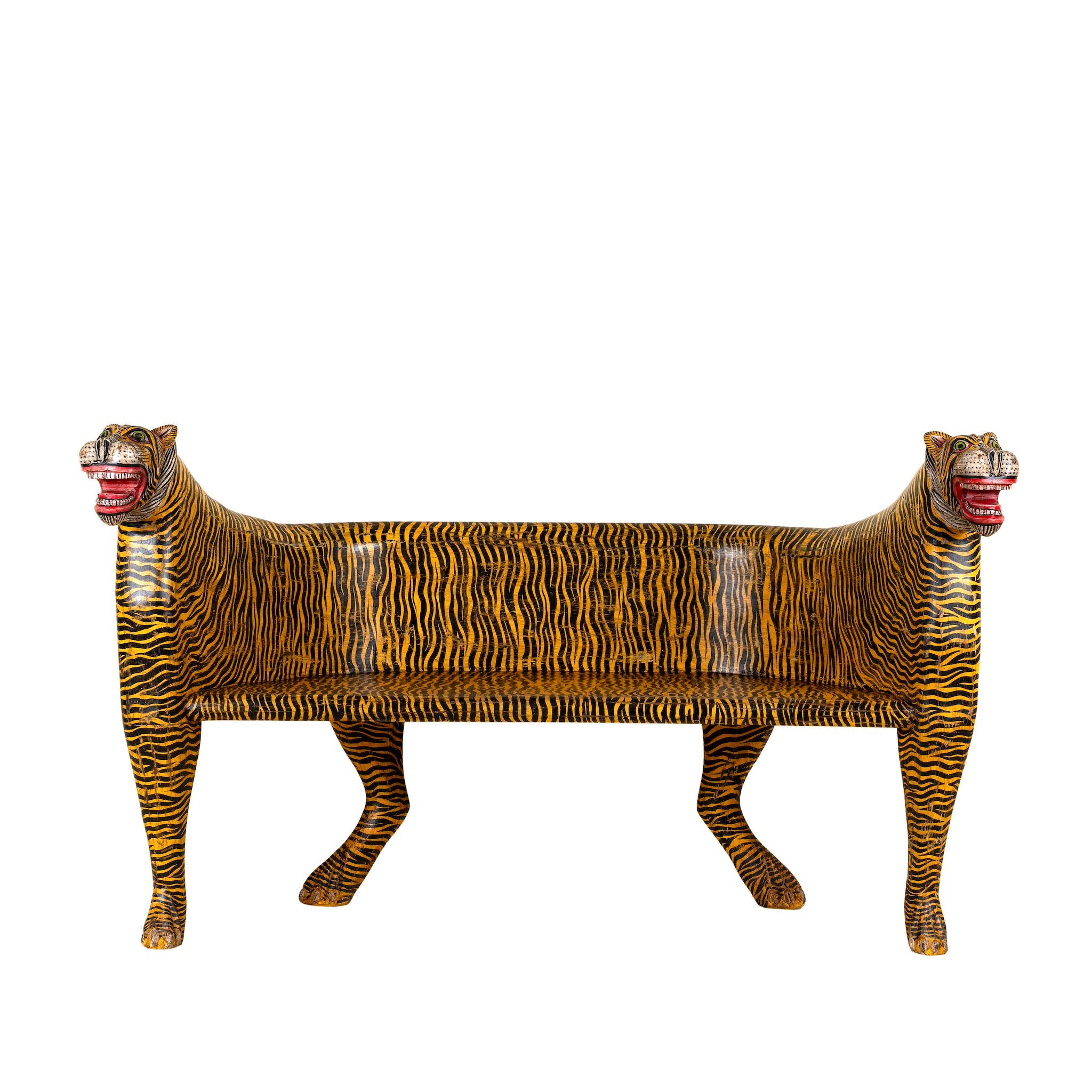White background image of a bold hand-painted bench made from reclaimed wood, designed with double tiger heads at each end and a vibrant yellow-and-black striped pattern throughout, combining whimsical animal form with striking folk-art flair.
