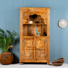 Hand-carved mango wood shelf with four compartments and an open shelf, featuring intricate floral patterns, in a bohemian style, with a bird figurine on the upper shelf.