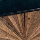 Close up of the marble top of a rustic-style cabinet made from reclaimed wood, featuring a striking sunburst pattern on the double doors, round metal pulls, and a contrasting black marble top that adds a refined touch to its natural, weathered look.
