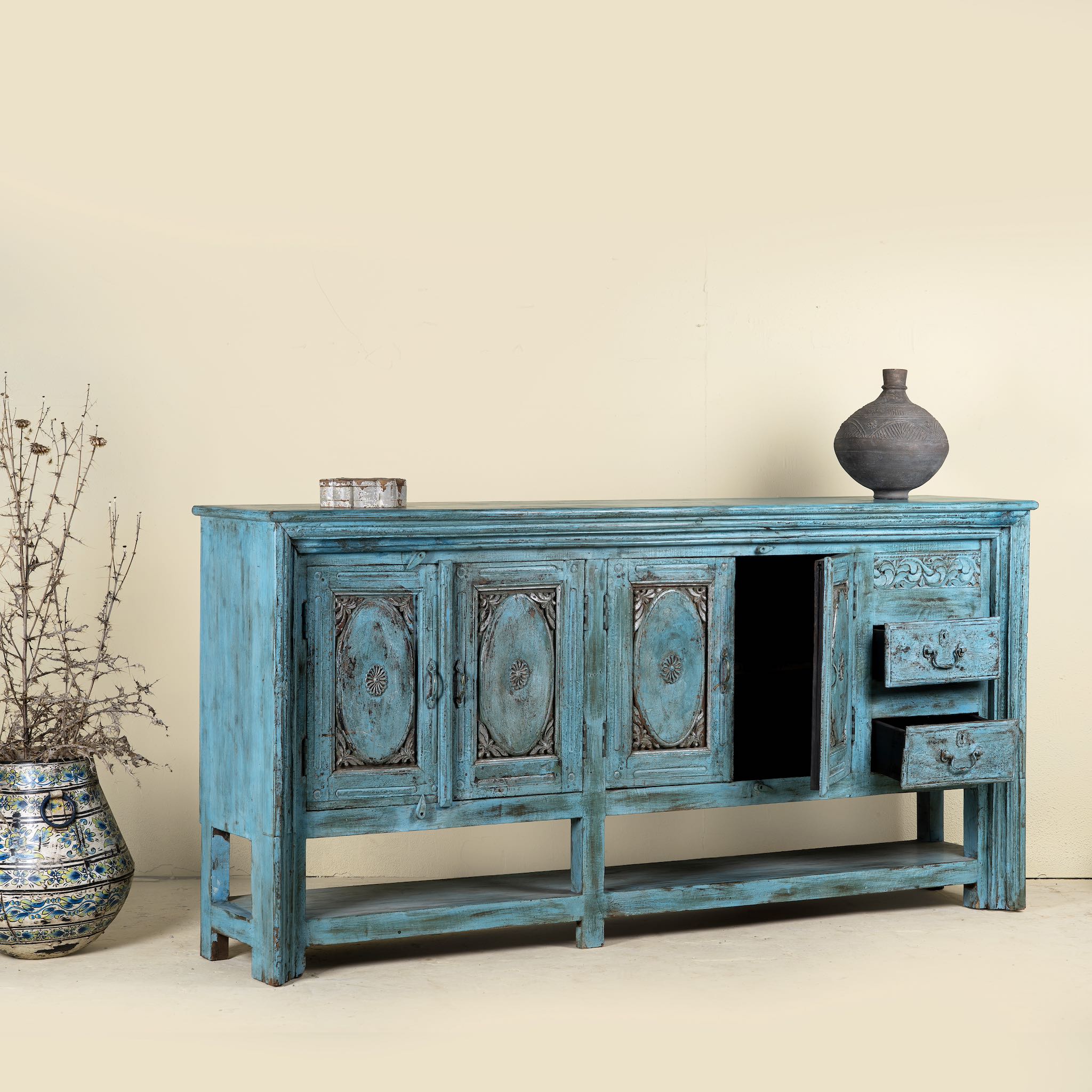 Vintage-style blue sideboard with decorative elements on a beige background