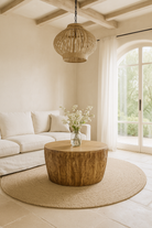 Lifestyle imagination of a round mango wood coffee table with hand-carved detailing and natural finish; rustic carved coffee table, 90 cm diameter, 52 cm height.