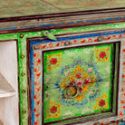 Close up image of a hand-painted reclaimed wood vintage lowboard with floral motifs – a colourful piece of sustainable furniture for artistic and rustic interiors.
