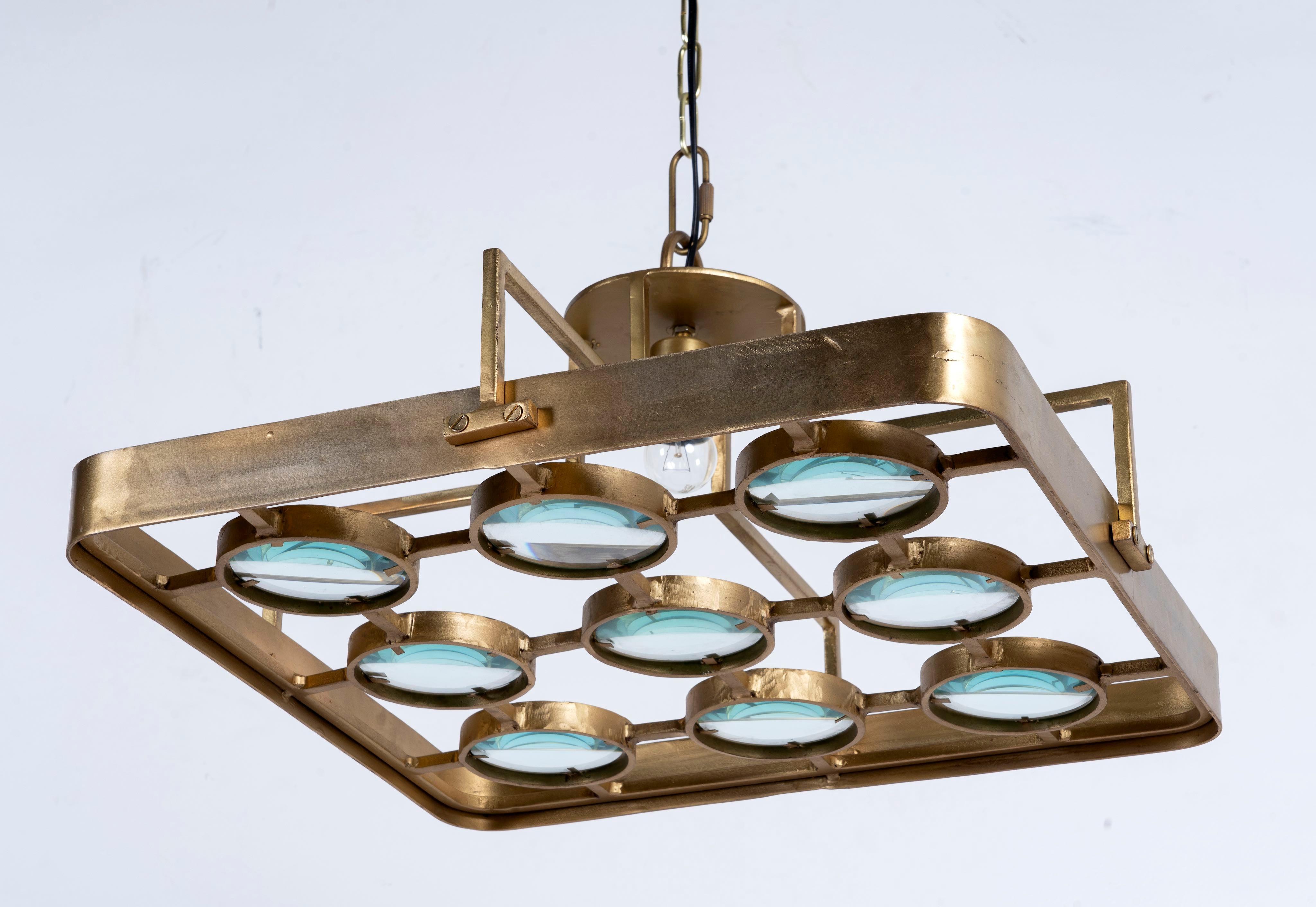 Side angle image of a unique pendant light with square brass-plated iron frame and magnifying blue and white glass inserts – a vintage lighting piece for kitchens, dining rooms, or living areas.