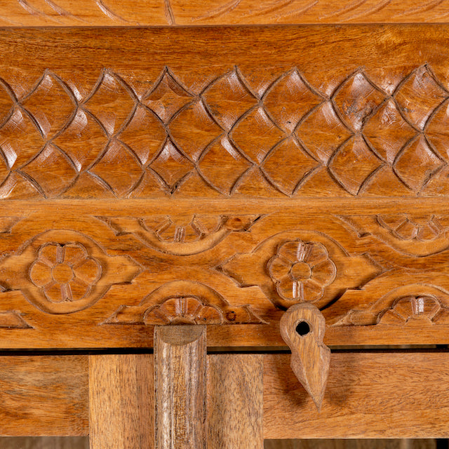 Close up image of a hand carved display cabinet made from natural mango wood with floral detailing and glass-panelled doors; 180 × 110 × 40 cm.