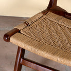 Close up image of an acacia wood chair with handwoven cotton rope seat and backrest; rustic wooden armchair for living rooms or lounges, 60 × 80 × 95 cm.