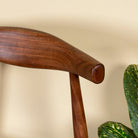 Close up image of an acacia wood chair with sculptural backrest, minimalist wooden armchair for dining or living rooms, 50 × 50 × 90 cm.