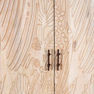 Close up image of a hand-carved mango wood wardrobe with sandblasted finish and iron stand; artisanal bedroom furniture, 90 × 46 × 183 cm.