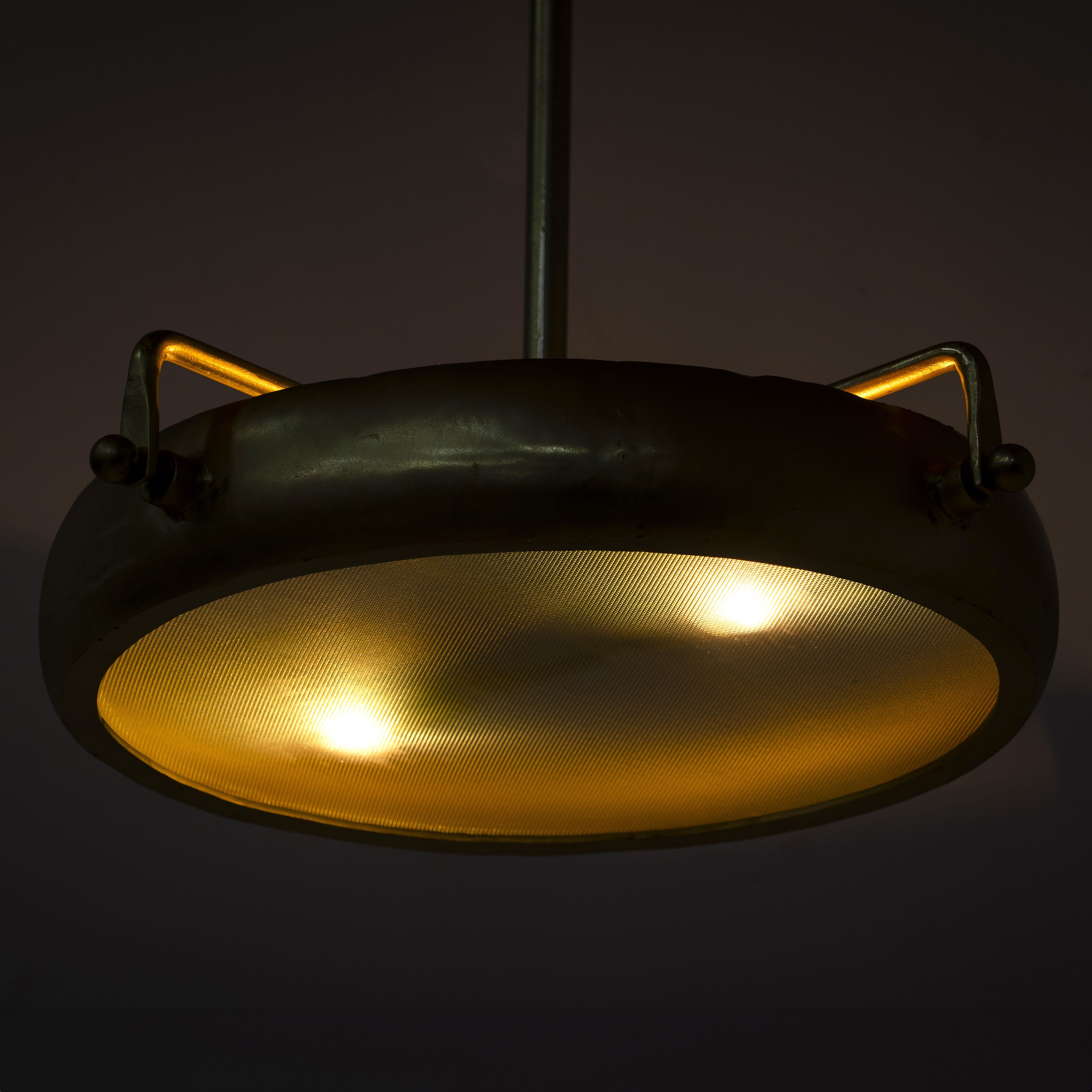 Image showing a lighted large round pendant lamp with clear hand-blown glass and brass-plated iron frame – retro lighting and artsy lamp ideal for kitchens, living rooms, or dining areas.