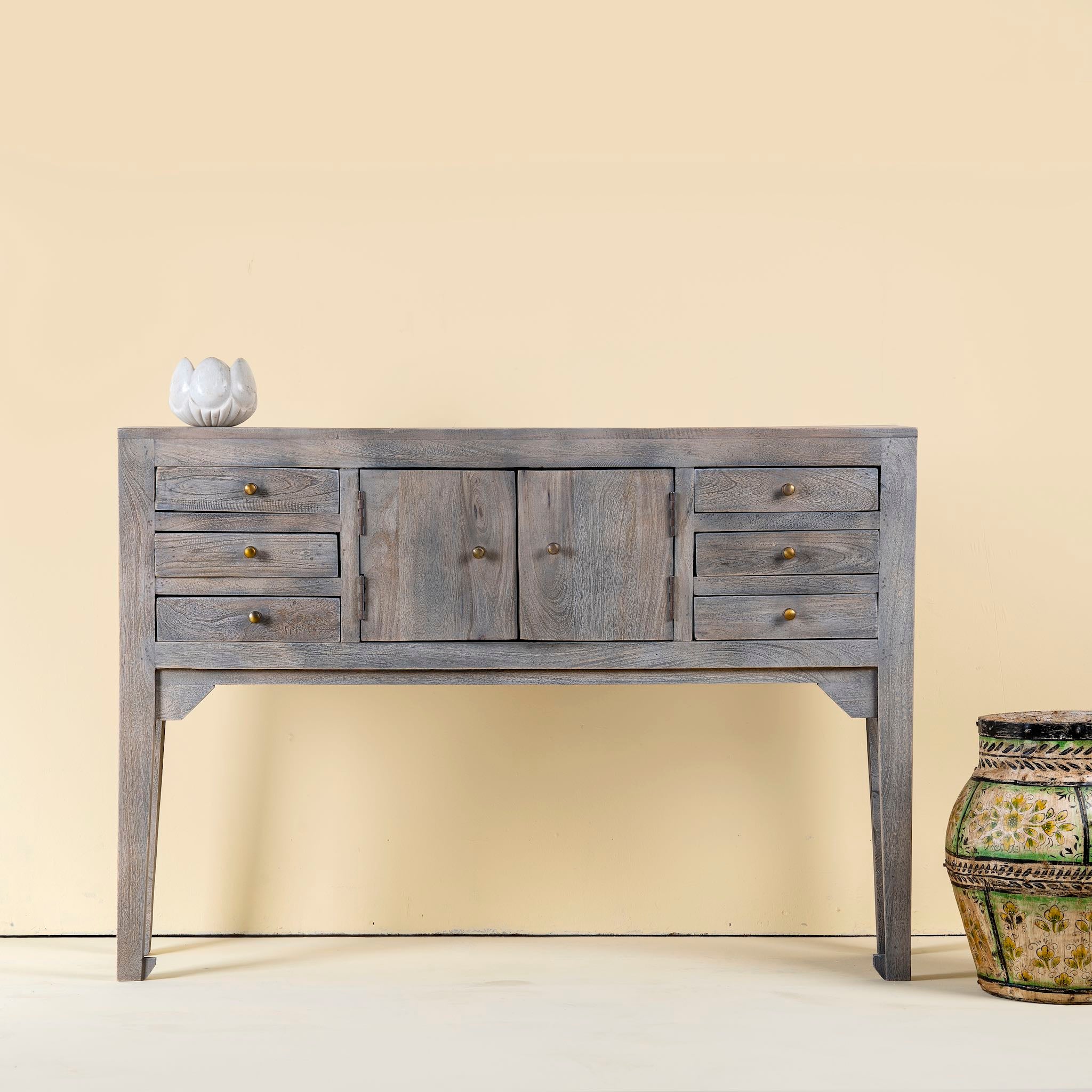 Wooden console table with drawers against a beige wall