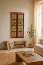 Lifestyle scene with a hand-painted antique teak wood Indian door with floral motifs, rustic orange frame, reclaimed wood vintage wall panels for bohemian and vintage home decor.