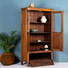 Side angle image with open door of a tall reclaimed teak wood display cabinet with two glass doors and a bottom drawer – wooden display cabinet crafted as sustainable furniture with natural elegance.