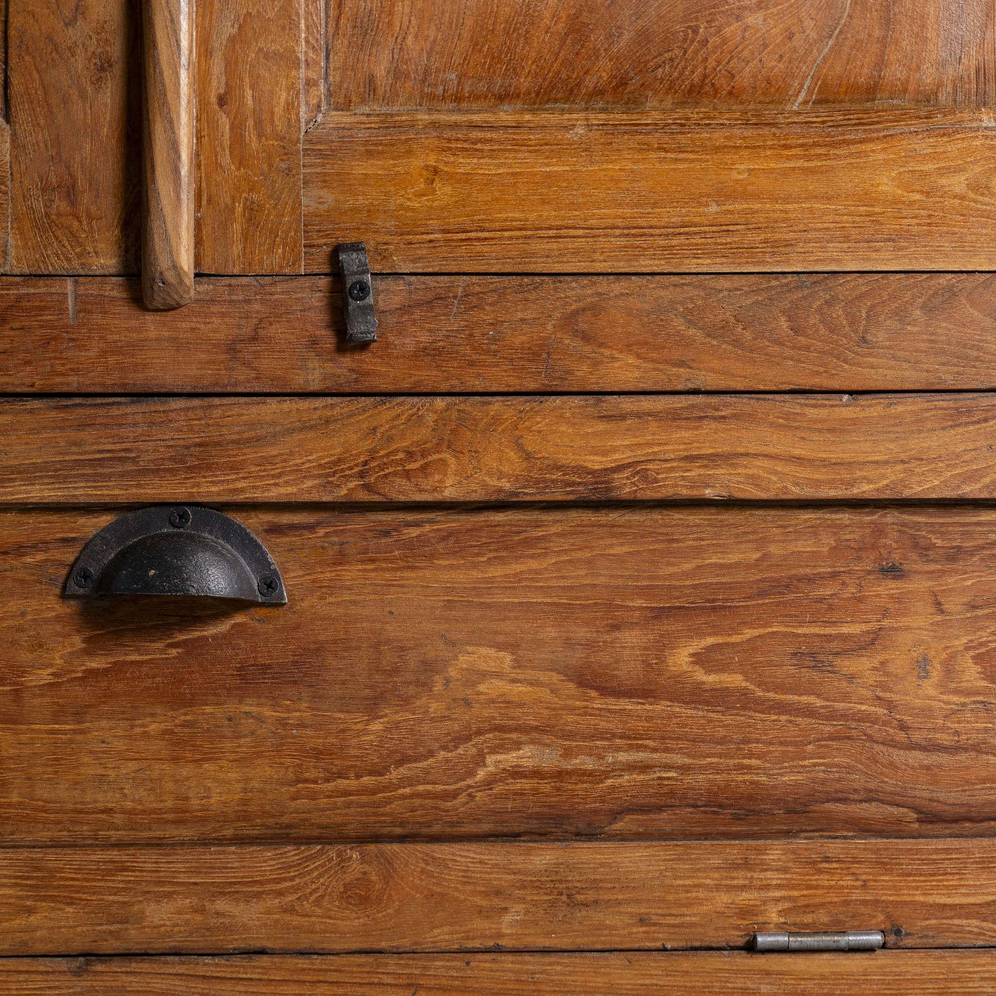 Close up image of a tall reclaimed teak wood display cabinet with two glass doors and a bottom drawer – wooden display cabinet crafted as sustainable furniture with natural elegance.