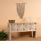 Side angle image of a reclaimed teak wood console table with hand-carved floral fronts and iron accents; sustainable furniture, 153 × 80 × 40 cm.