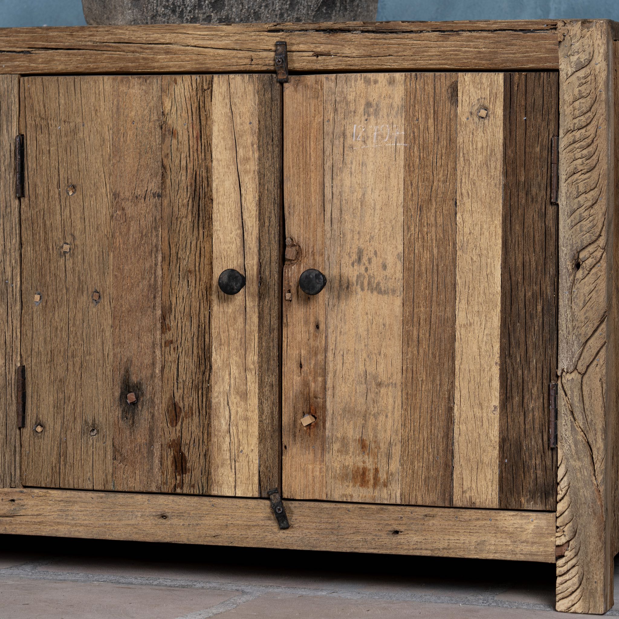 Close up image of a large sideboard in Driftwood/ Wabi Sabi style made from recycled old wood, featuring four cabinet doors, two central drawers, and an open shelf with a naturally aged, rustic finish.

