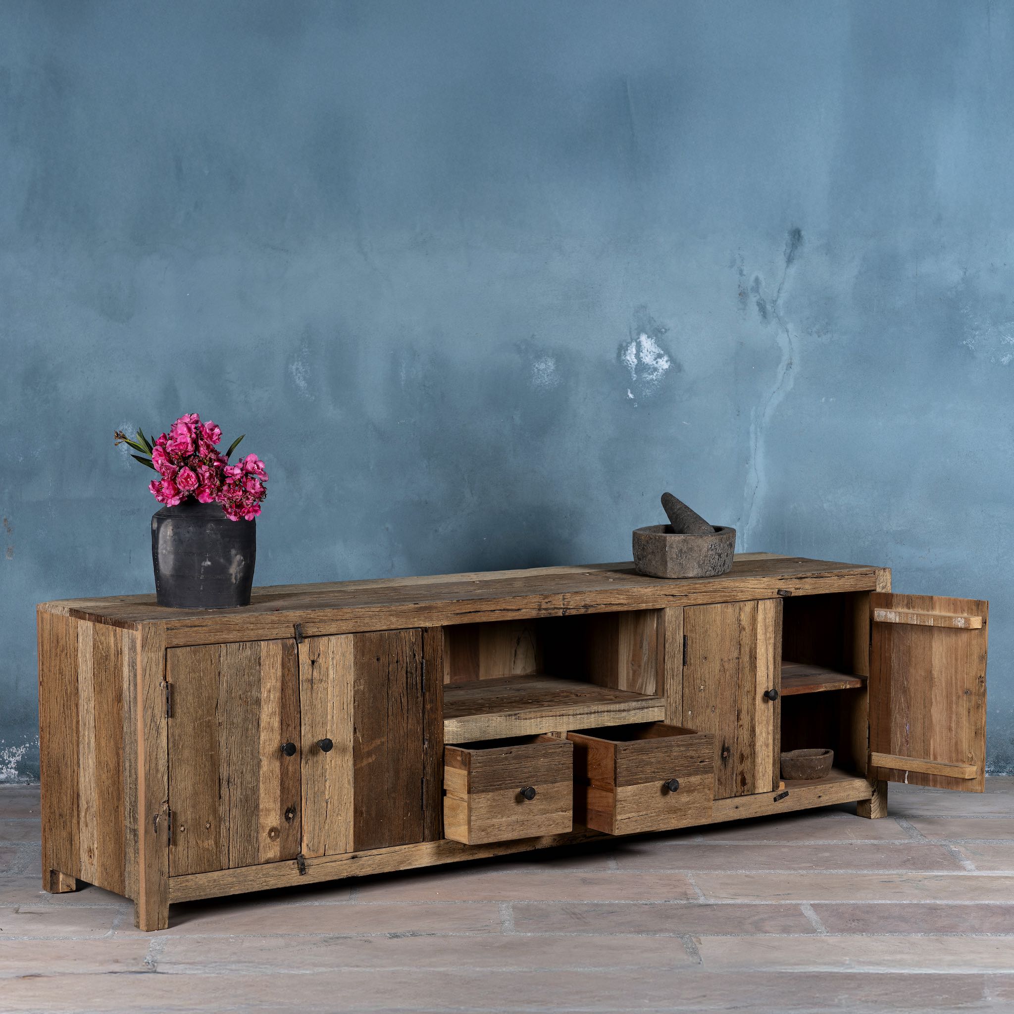Side view with open drawers image of a large sideboard in Driftwood/ Wabi Sabi style made from recycled old wood, featuring four cabinet doors, two central drawers, and an open shelf with a naturally aged, rustic finish.

