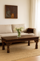 Lifestyle imagination of a rectangular teak wood coffee table with hand-carved Indian detailing, reclaimed wood finish, and iron accents; 158 × 76 × 46 cm.