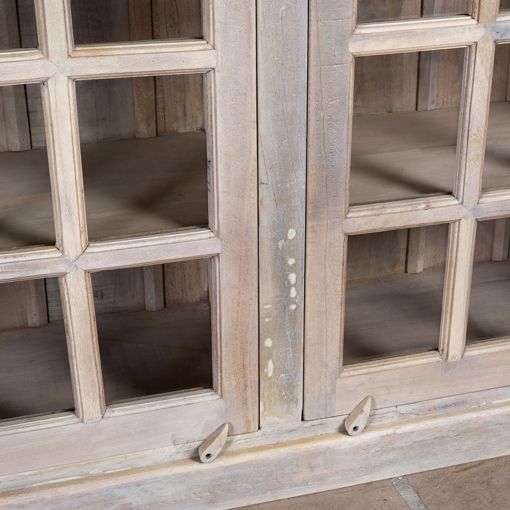 Close up image of a tall reclaimed wood cabinet in sandblasted vintage design with glass-panelled doors; rustic living room furniture, 100 × 40 × 190 cm.
