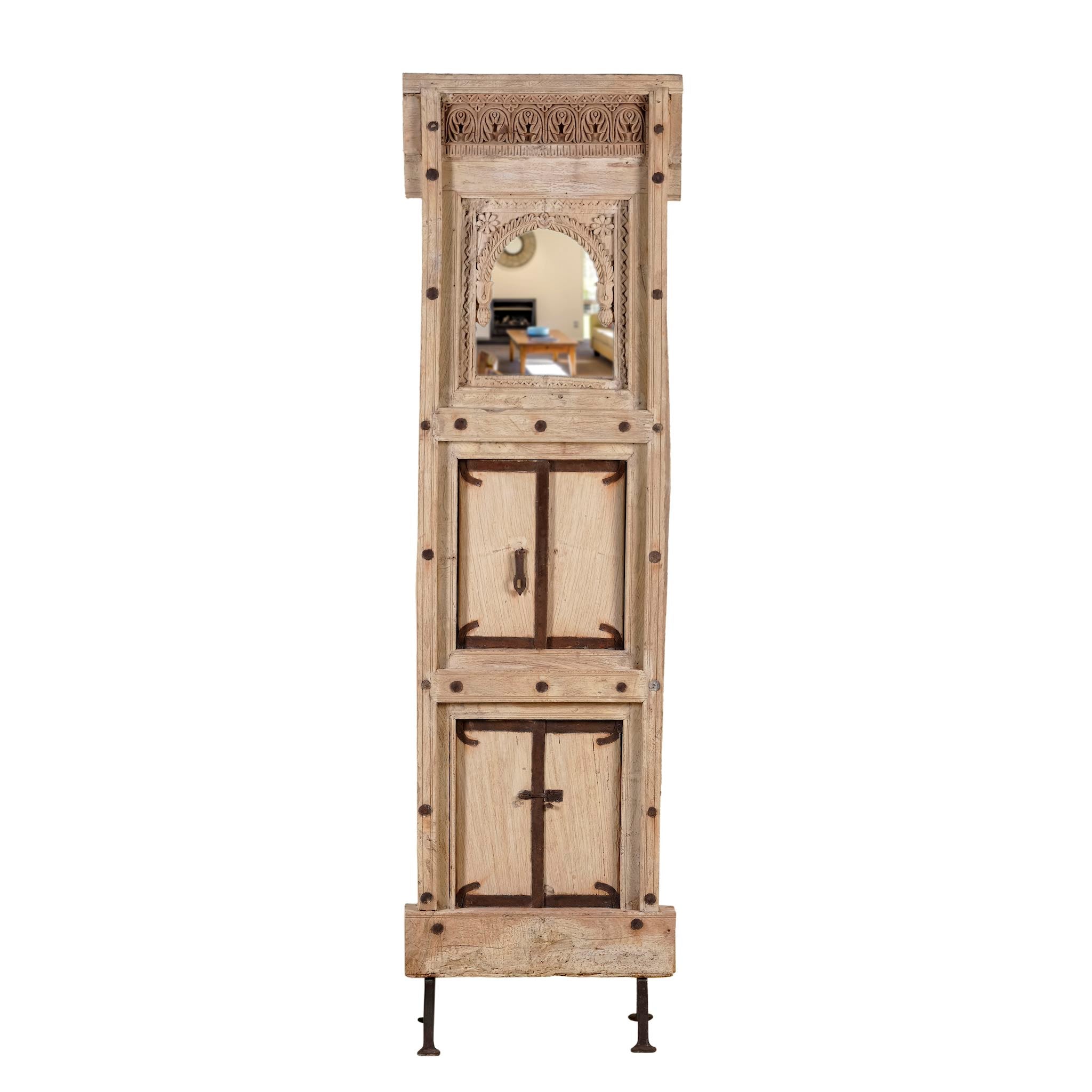 White background image of a mirror stand crafted from reclaimed teak wood with intricate carved detailing and two storage cabinets, set on a sturdy iron base, blending rustic charm with vintage Indian architectural elements.
