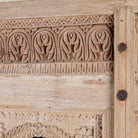 Close up image of a mirror stand crafted from reclaimed teak wood with intricate carved detailing and two storage cabinets, set on a sturdy iron base, blending rustic charm with vintage Indian architectural elements.
