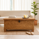 Lifestyle image of a hand-carved mango wood storage chest with floral detailing and iron fittings – wooden carved chest ideal for use as elegant bedroom furniture or storage.