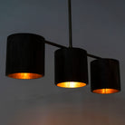 Image showing a lighted version of a long wooden pendant light with brass-lined interior and three lights – vintage lighting with natural grain finish, perfect for kitchens, dining areas, or living rooms.