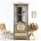 A vintage-style Pattanur showcase cabinet with hand-painted floral and geometric patterns, featuring a bird perched on a shelf with decorative items.