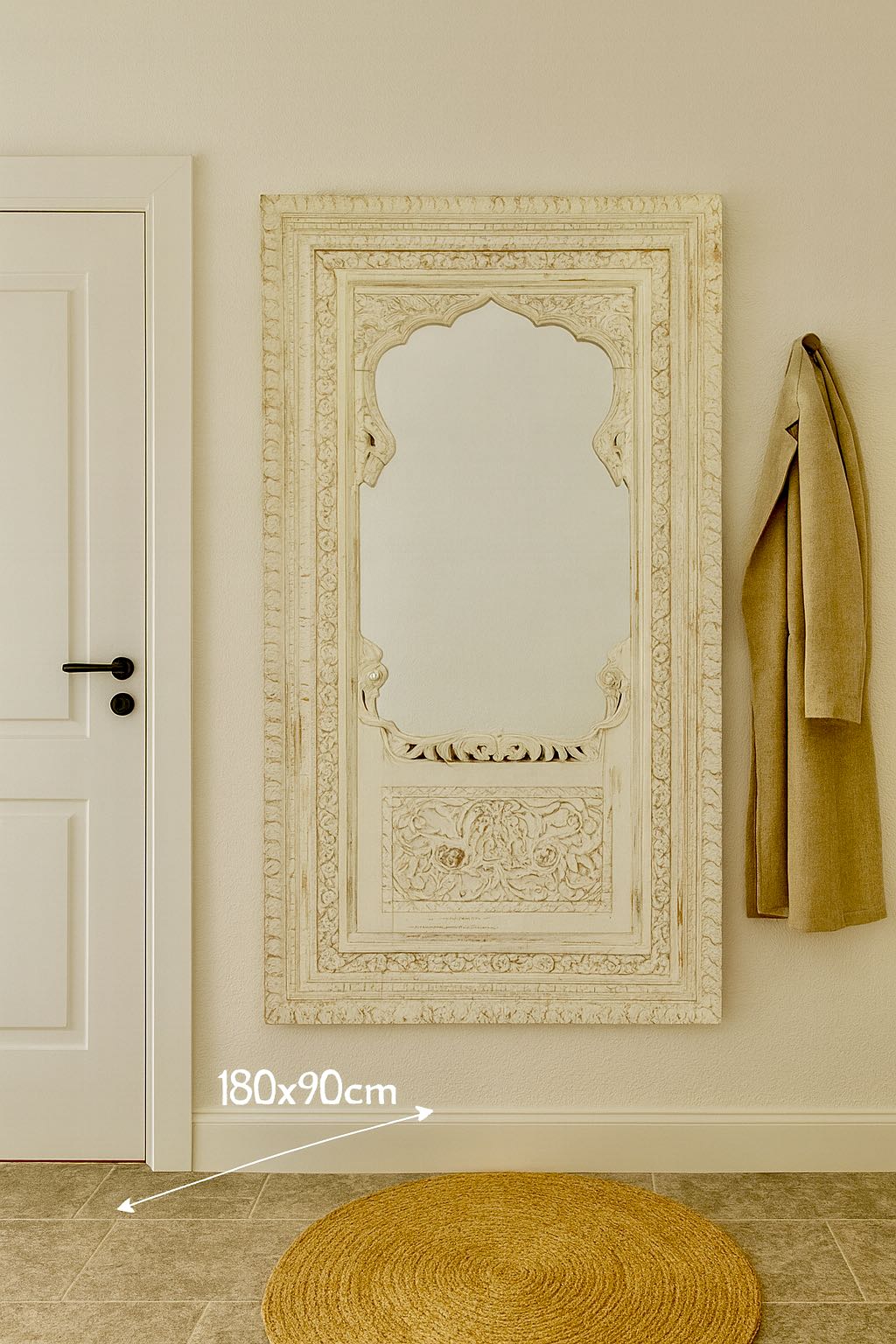 Lifestyle image of a tall white washed wall mirror with intricately hand carved mango wood frame; 190 × 109 × 10