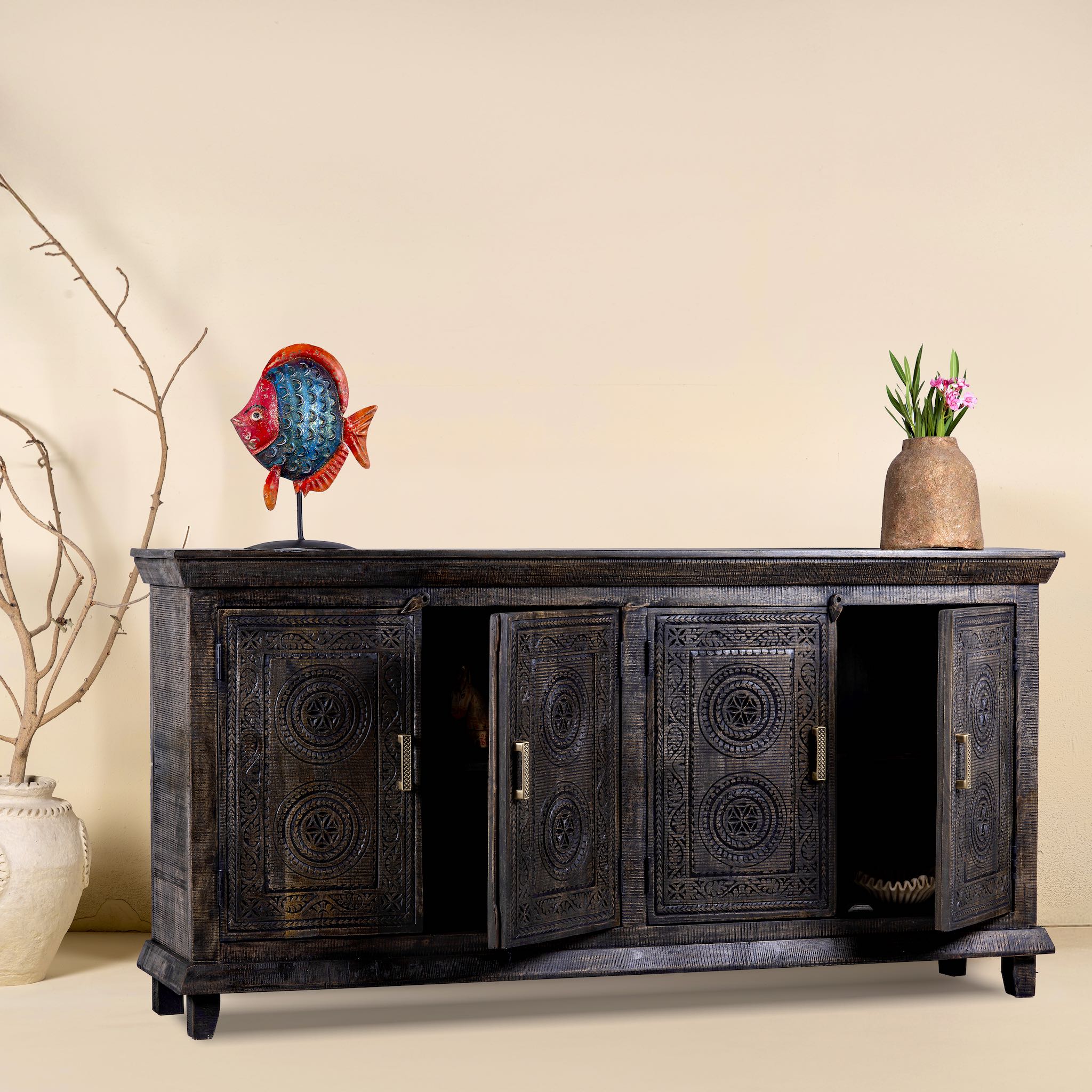 Side view with open doors of a black mango wood sideboard with intricate hand-carved geometric patterns and four cabinet doors, styled with decorative accents on top.