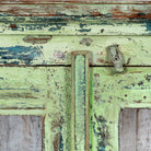 Close up image of a refurbished teak wood showcase with distressed green finish – sustainable furniture with boho style interior appeal and glass-panelled storage.