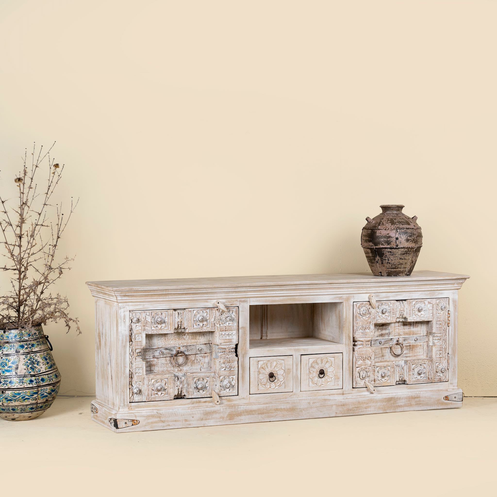 Side angle view of a Low board made from reclaimed teak wood door panels, featuring detailed carvings, iron ring handles, and ample storage space in a whitewashed vintage finish.