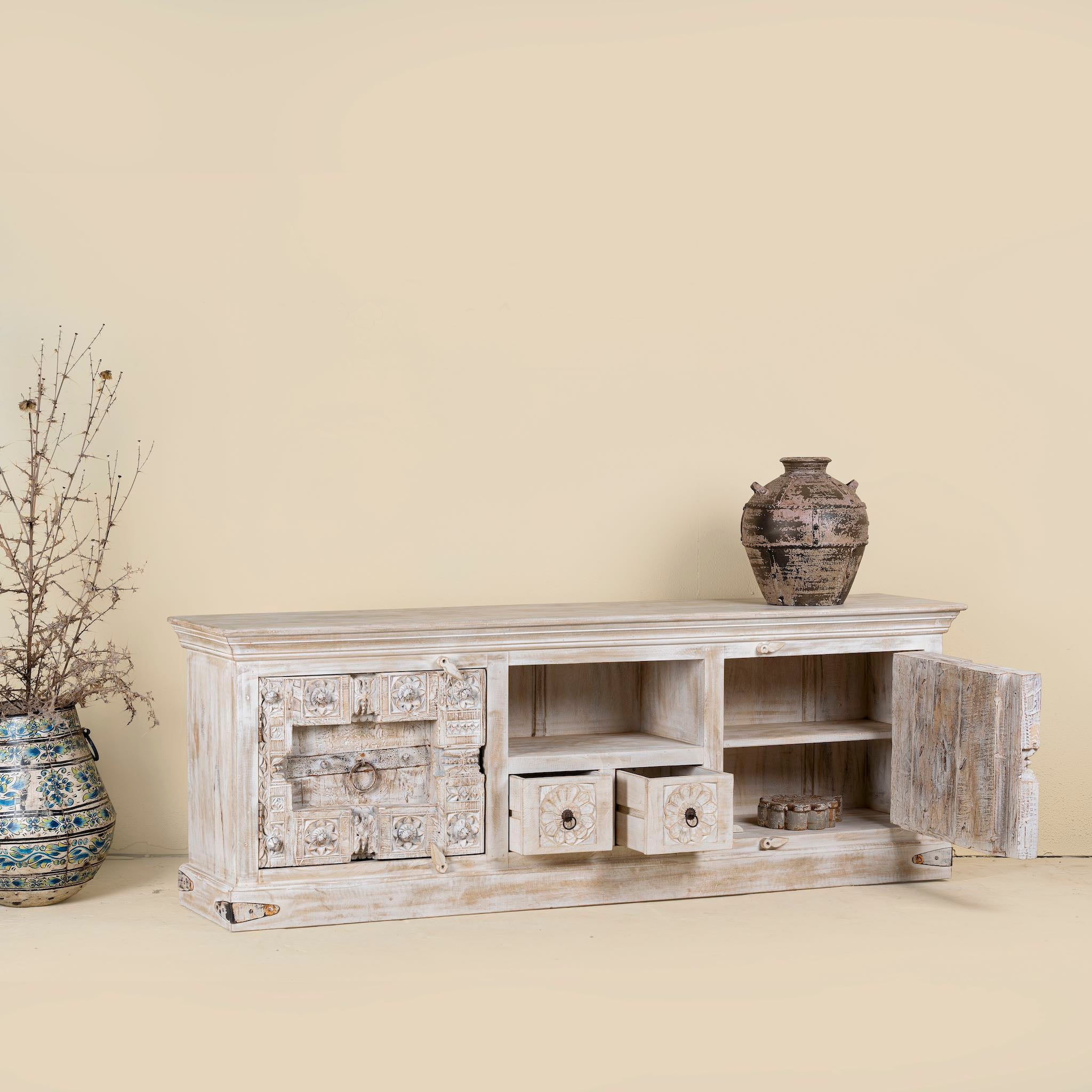 Low board made from reclaimed teak wood door panels, featuring detailed carvings, iron ring handles, and ample storage space in a whitewashed vintage finish.