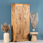 Side angle image of a hand-carved mango wood cabinet with traditional Indian village scenes – Rewalsar by Om Home & Garden, carved wooden furniture with cultural depth for bedroom interiors.