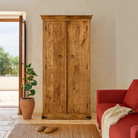 Lifestyle imagination of a hand-carved mango wood cabinet with traditional Indian village scenes – Rewalsar by Om Home & Garden, carved wooden furniture with cultural depth for bedroom interiors.