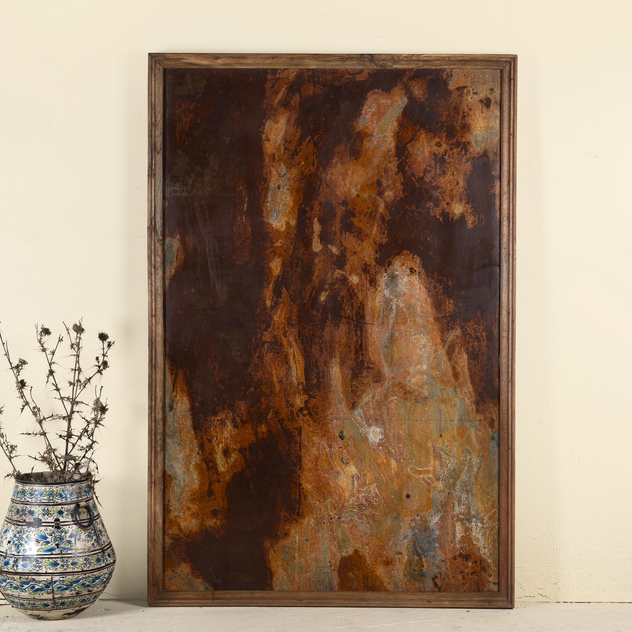 Decorative wall panel featuring naturally rusted metal with a reclaimed teak wood frame, showcasing an abstract, earthy patina finish.

