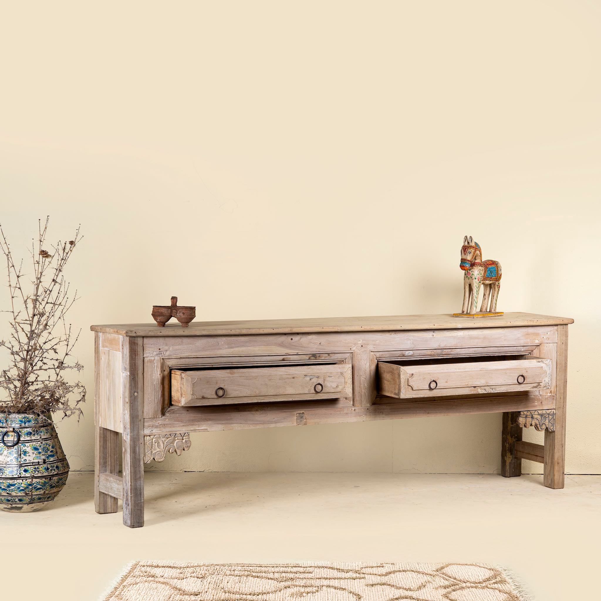 Wooden console table with two drawers against a beige wall