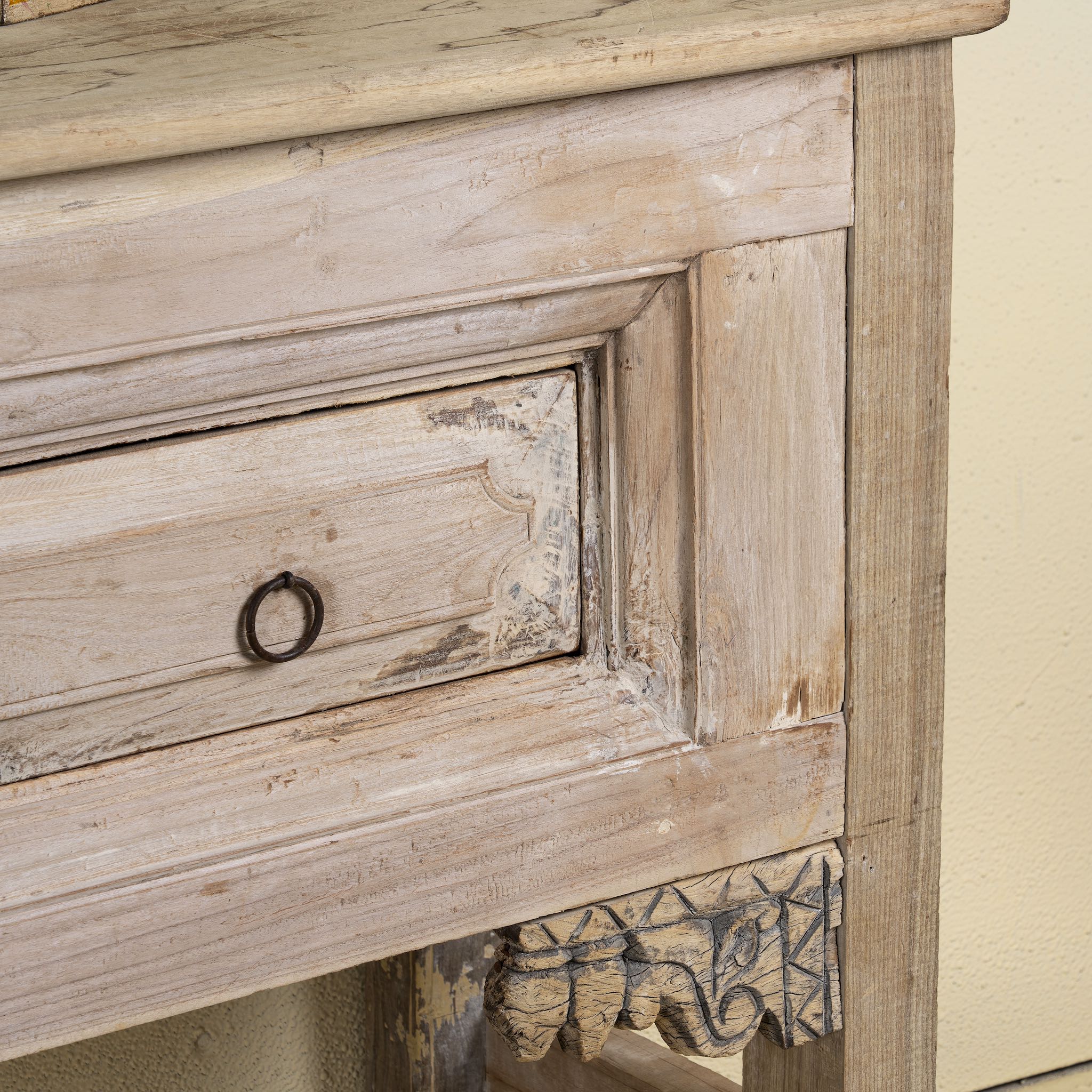 Close-up of a wooden dresser with a drawer and decorative carvings.