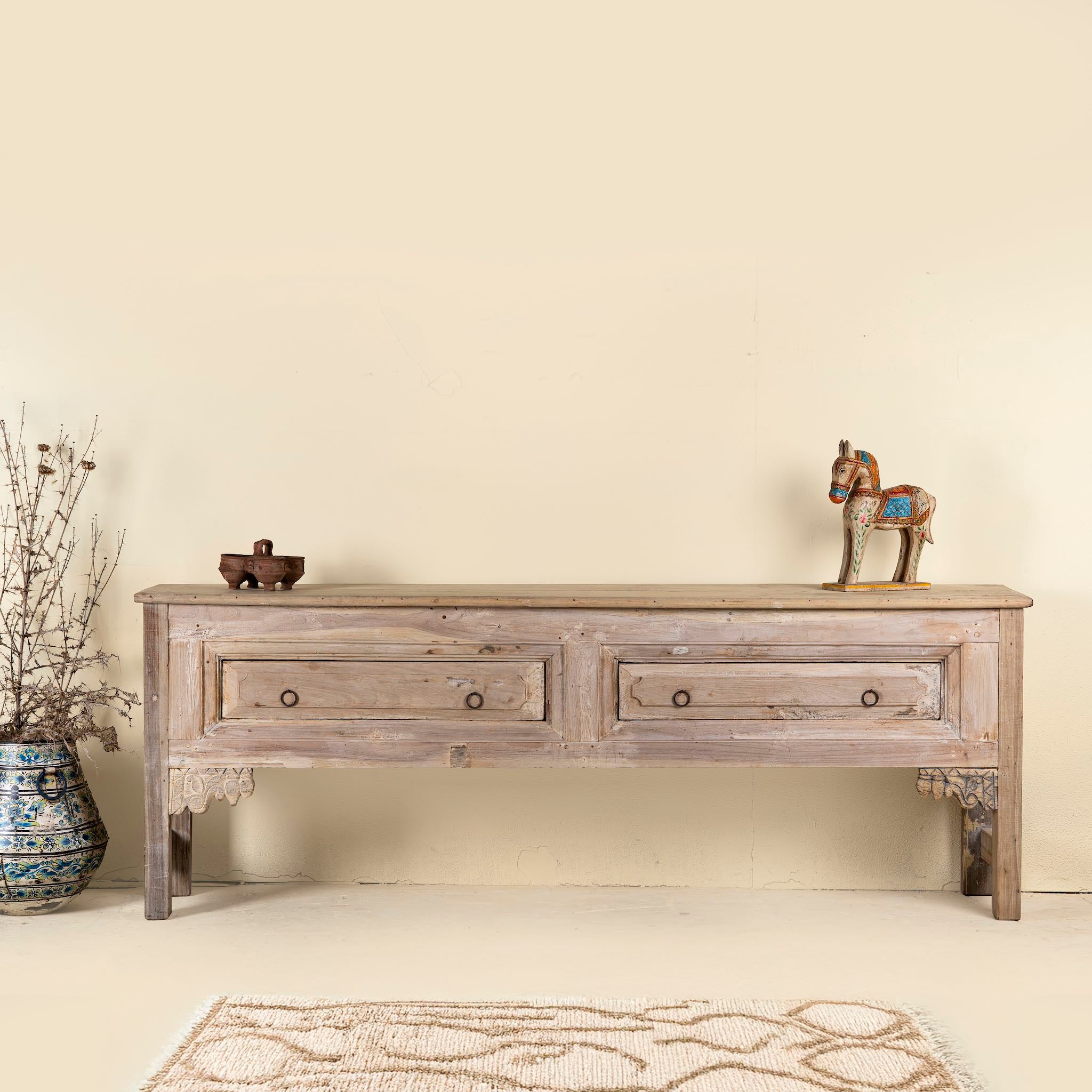 Vintage-style teak console table with two spacious drawers, simple carved brackets, and a natural bleached wood finish for a clean rustic look.