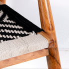 Close up image of a acacia wood chair with black-and-white handwoven cotton rope seat and backrest; artisanal wooden armchair, 61 × 47 × 83 cm.