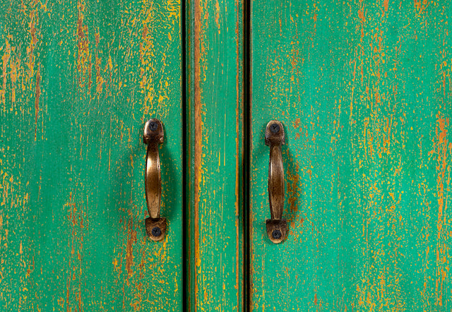 Close up image of a handcrafted sideboard made from reclaimed teak and recycled wood, hand-painted in green – sustainable furniture with artistic character.
