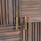 Close up image of a grey carved cabinet in mango wood with linear carvings and brass‑plated iron base, 92 × 42 × 115 cm.