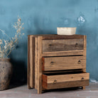 Side view image with open drawer of a three-drawer dresser in Driftwood/Wabi Sabi style made from recycled old wood, featuring a naturally weathered finish with visible grain patterns and metal ring pull handles for a rustic, handcrafted look.

