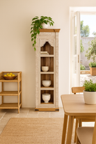 Lifestyle image of a hand carved white washed mango wood bookshelf with Mediterranean design – narrow wooden furniture piece with decorative carving and natural charm.