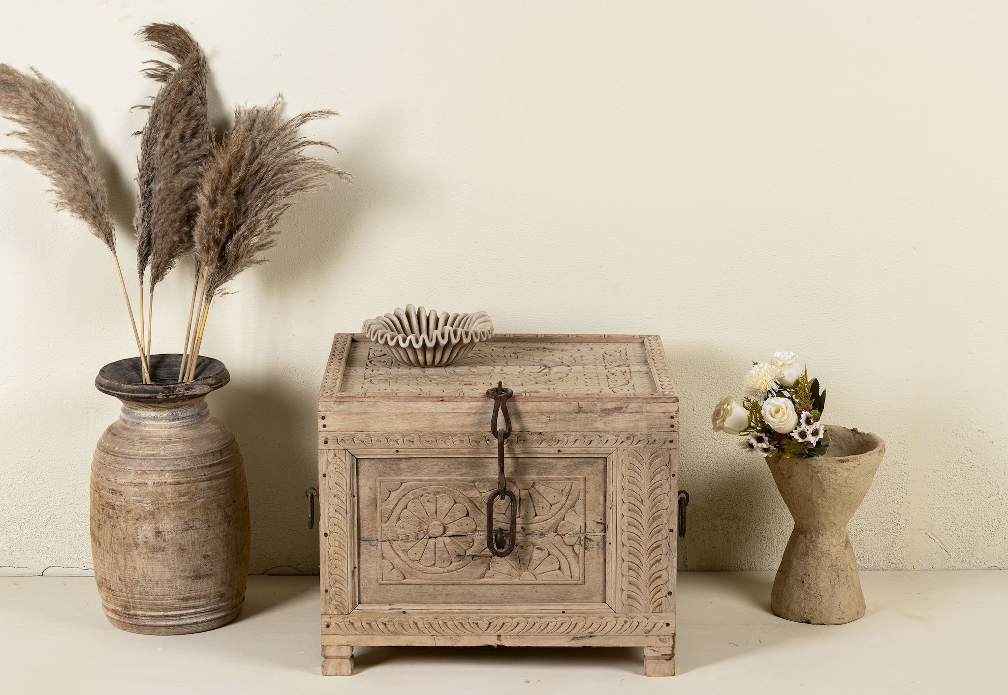 Hand-carved storage chest made from reclaimed teak wood, showcasing intricate floral and geometric patterns on all sides, with a rustic natural finish and a vintage-style iron latch and handles.
