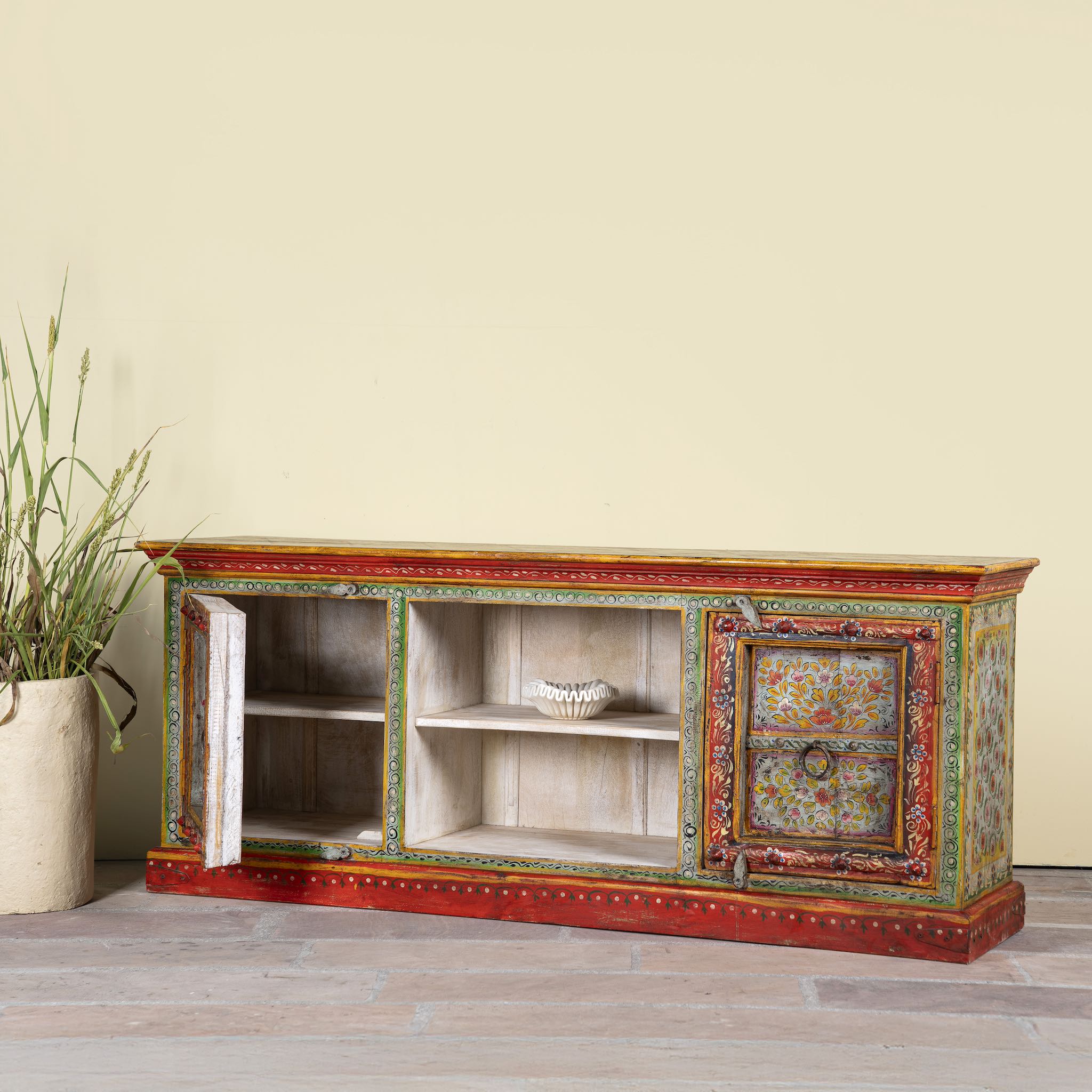 Side angle image showing open door of a hand-painted reclaimed wood vintage lowboard with floral motifs – a colourful piece of sustainable furniture for artistic and rustic interiors.