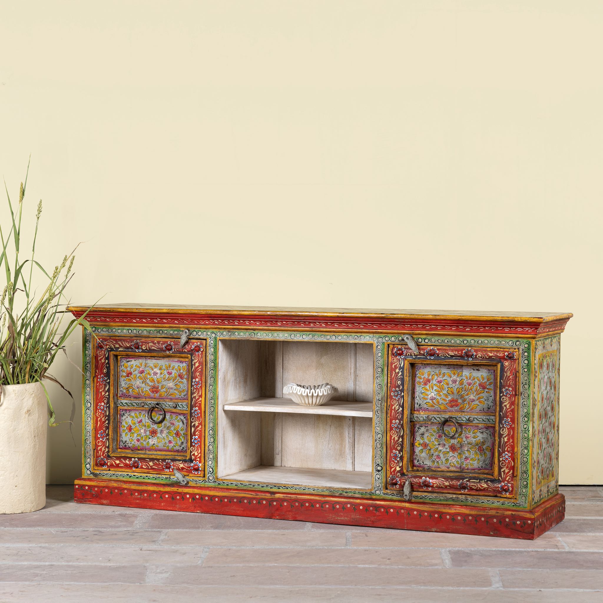 Side angle image of a hand-painted reclaimed wood vintage lowboard with floral motifs – a colourful piece of sustainable furniture for artistic and rustic interiors.