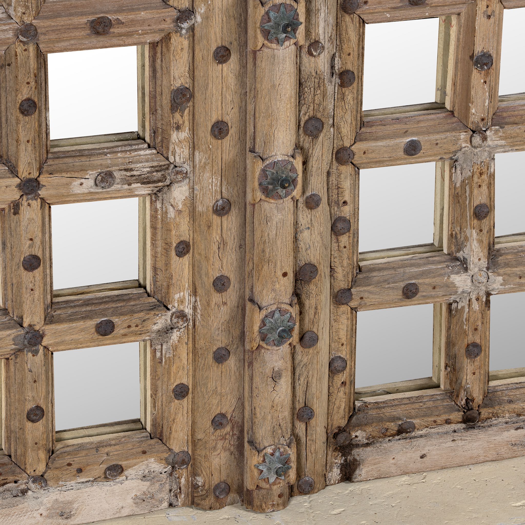 Close-up of a wooden gate with metal studs on a plain background