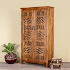 Side angle image of a hand-carved mango wood wardrobe with floral and lattice motifs – a detailed piece of carved wood furniture ideal for natural mango wood interiors.