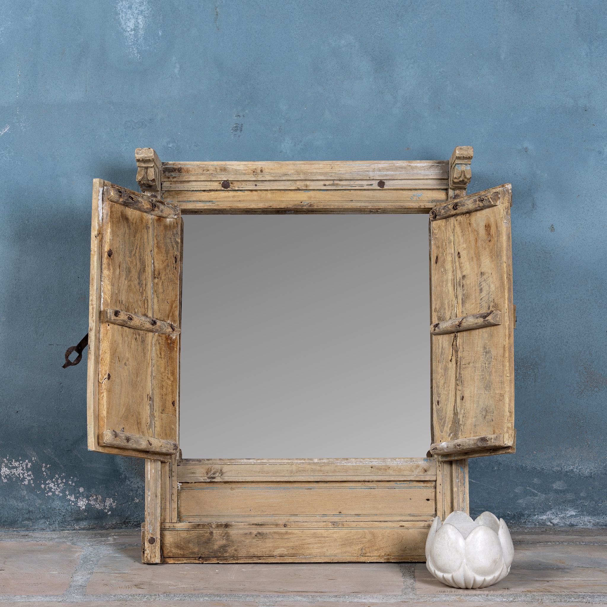 Wooden shutter-style mirror with a blue textured wall background